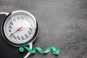 Scales and measuring tape on grey background Weight loss concept