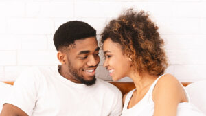 Loving black couple relaxing in bed at home