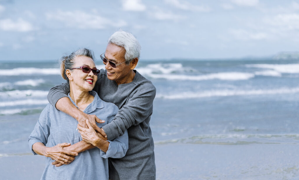 Asian senior couple or elderly people walking and siting at the beach on their weekend vacation holiday Retirement vaction concept